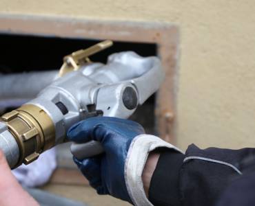 A man transporting oil using a hose