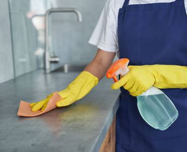 Woman cleaning commercial kitchen countertop