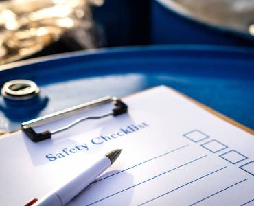 A safety checklist clipboard on top of a metal barrel