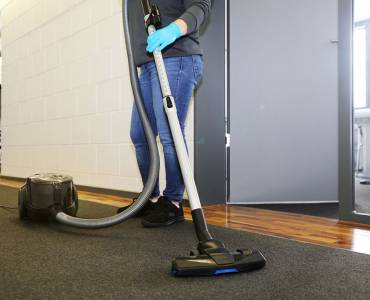 A cleaner vacuuming the corridor of an office