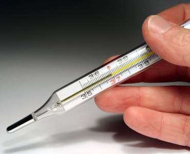 Someone holding a mercury thermometer