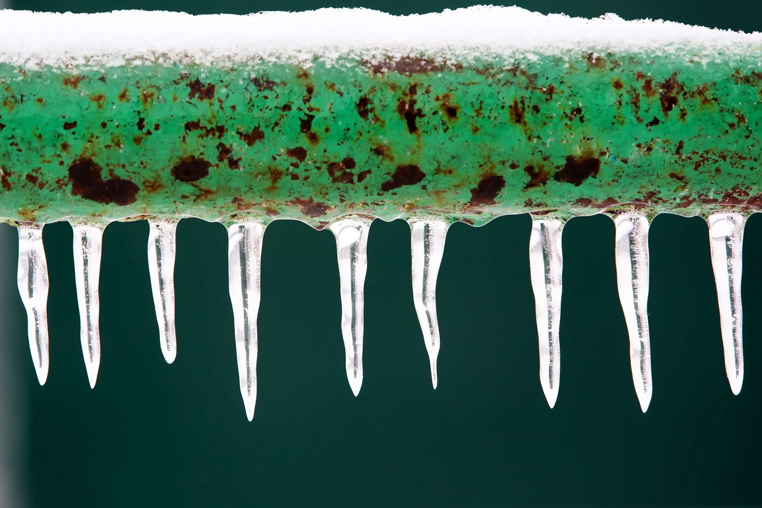 Snow and icicles on frozen pipe