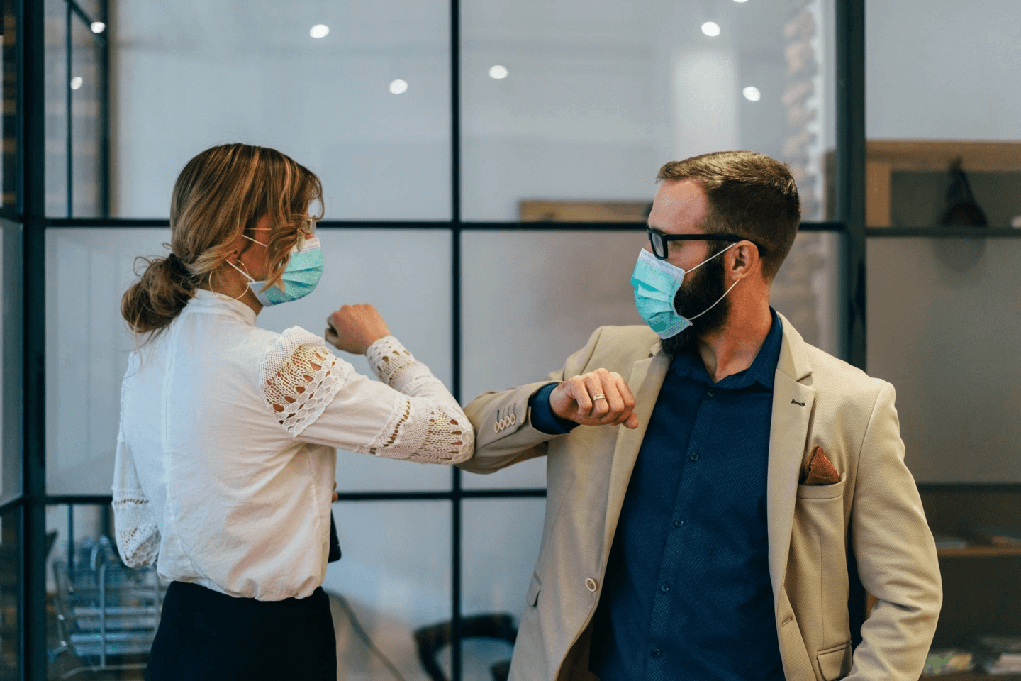 Two colleagues elbow bump, whilst wearing face masks