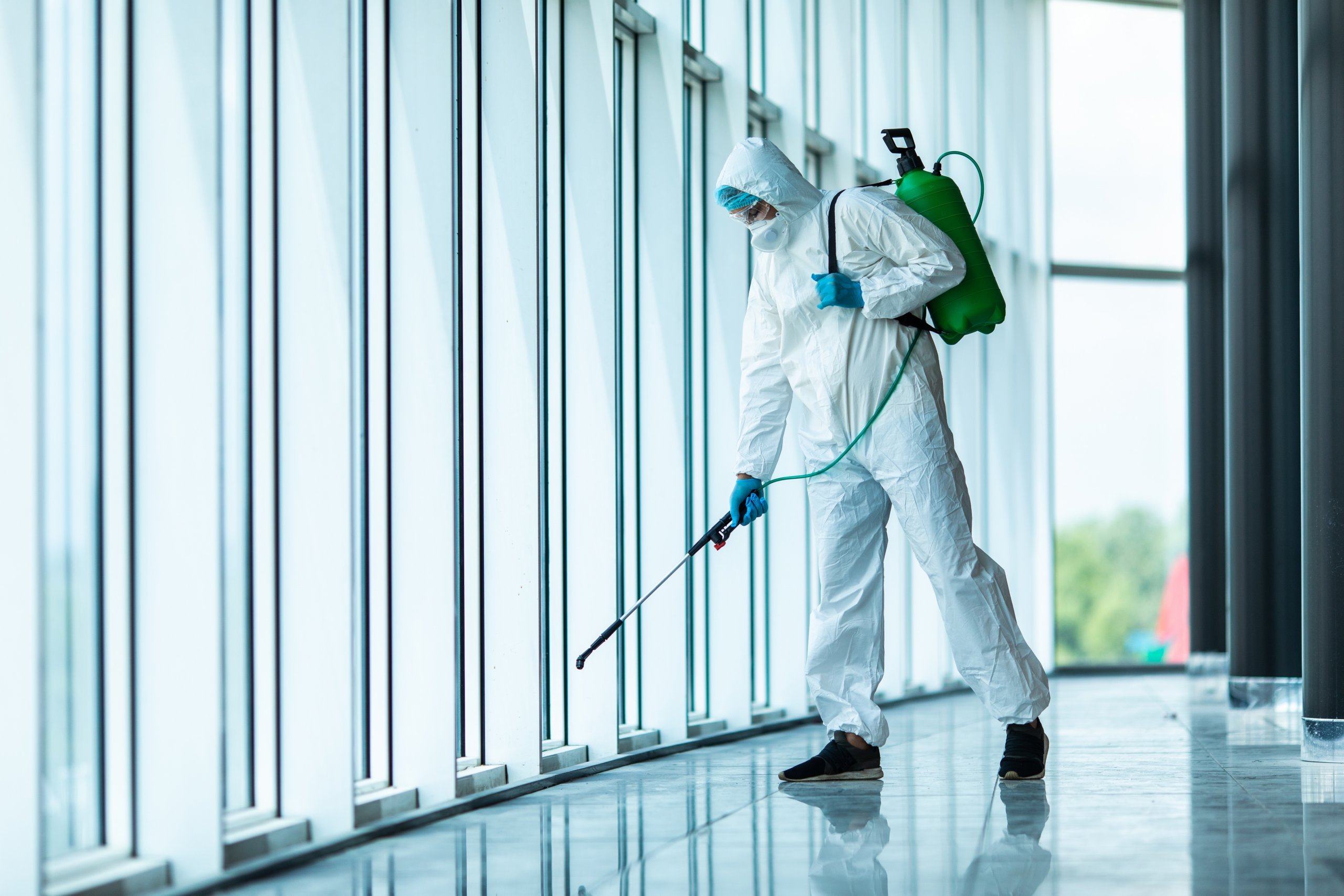 Man in full PPE sanitising room