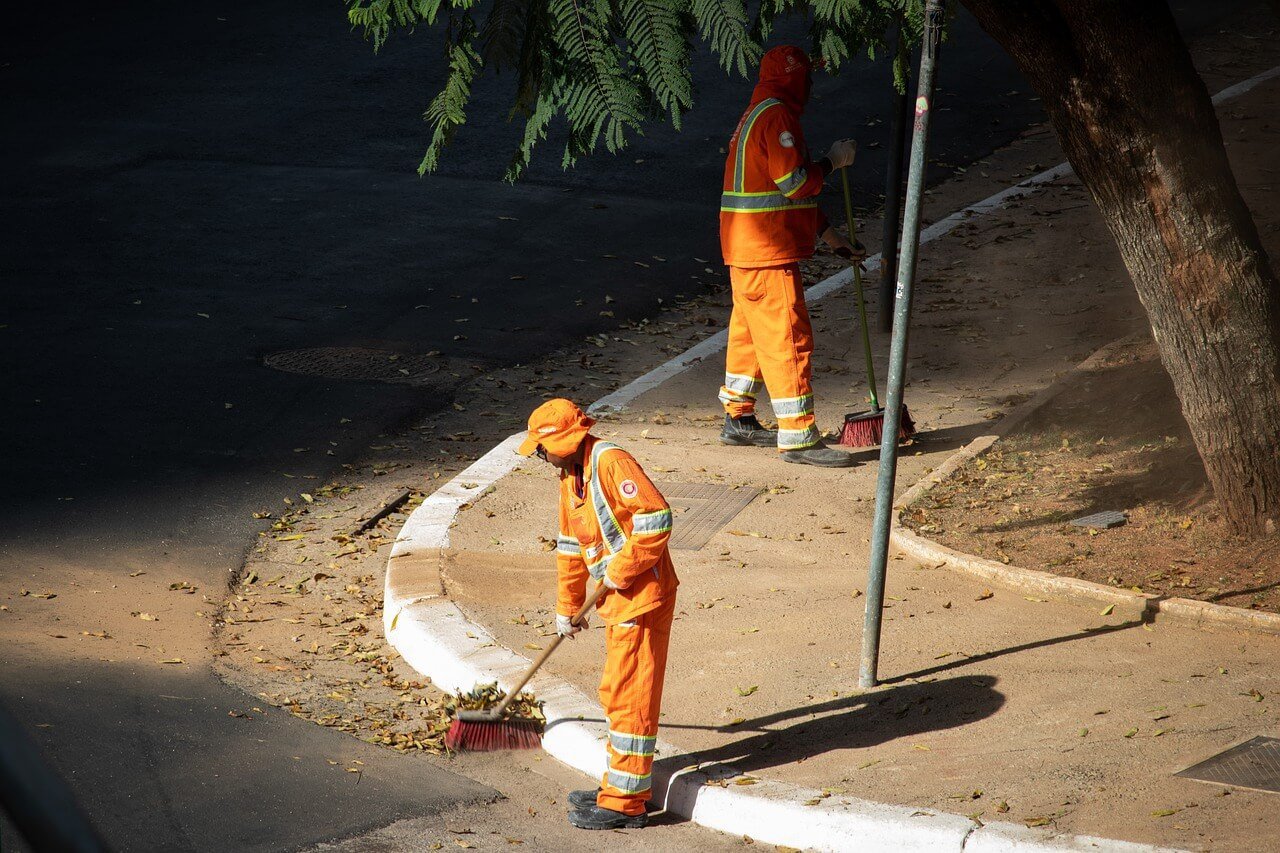 Two men road sweeping in hi-vis