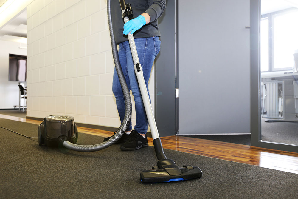 A cleaner vacuuming the corridor of an office