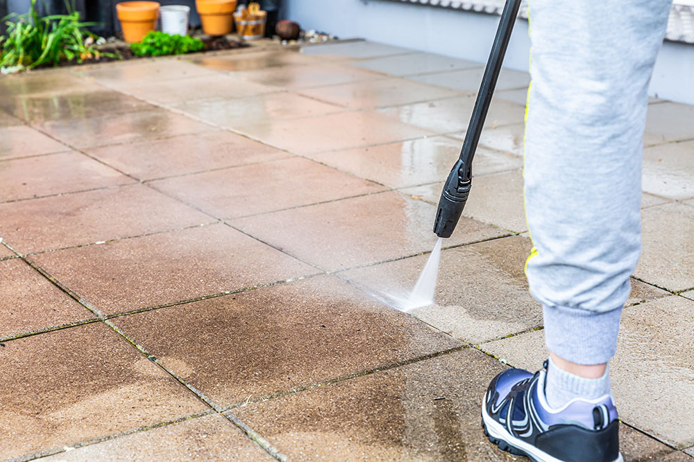 Someone pressure washing their garden stone terrace