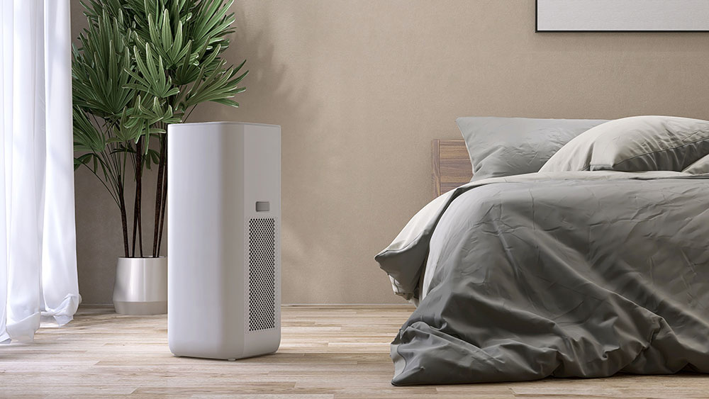 A dehumidifier in a bedroom beside a bed