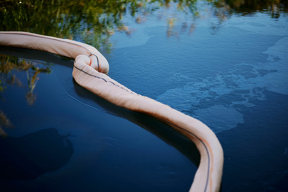 Top view of oil absorbent netted boom on the surface of a river