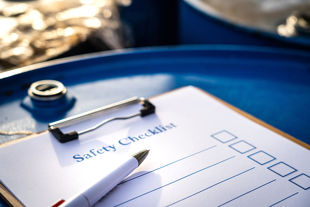 A safety checklist clipboard on top of a metal barrel