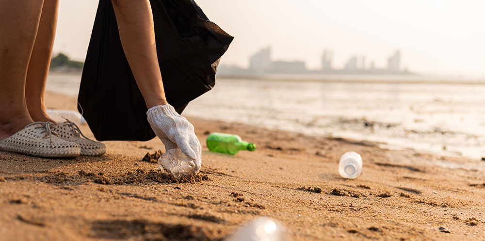 Person cleaning plastic bottles off the beach