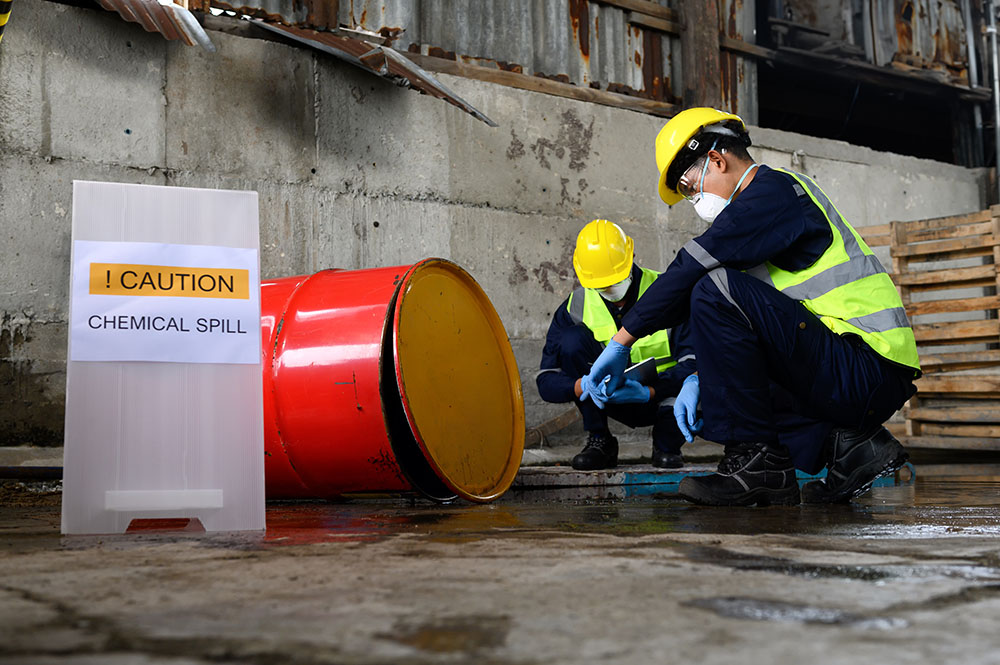 Two people assessing a liquid chemical spill on the ground