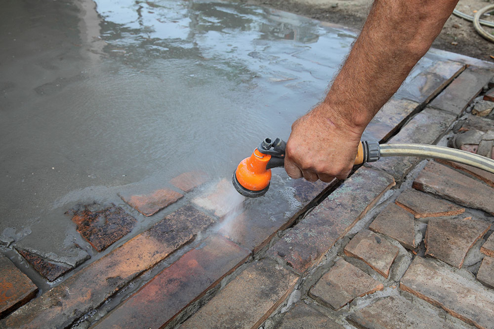 Man cleaning brick patio