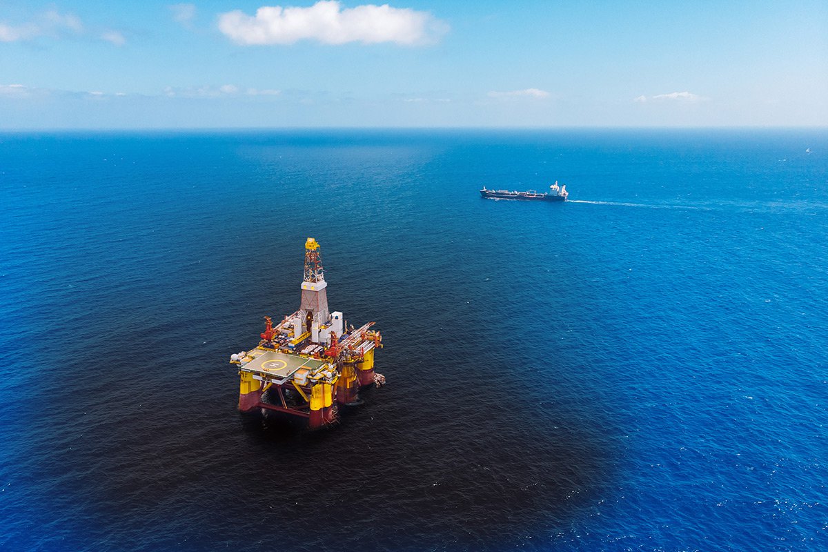 Oil rig out at sea with passing boat