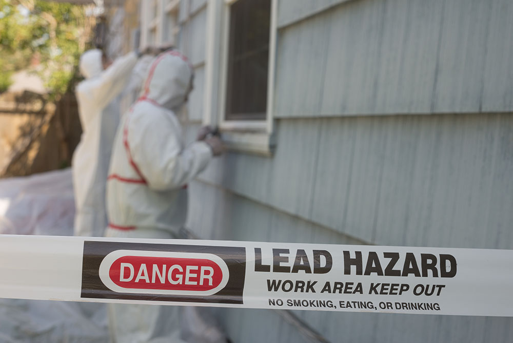 Lead pant hazard tape in front of a painted house