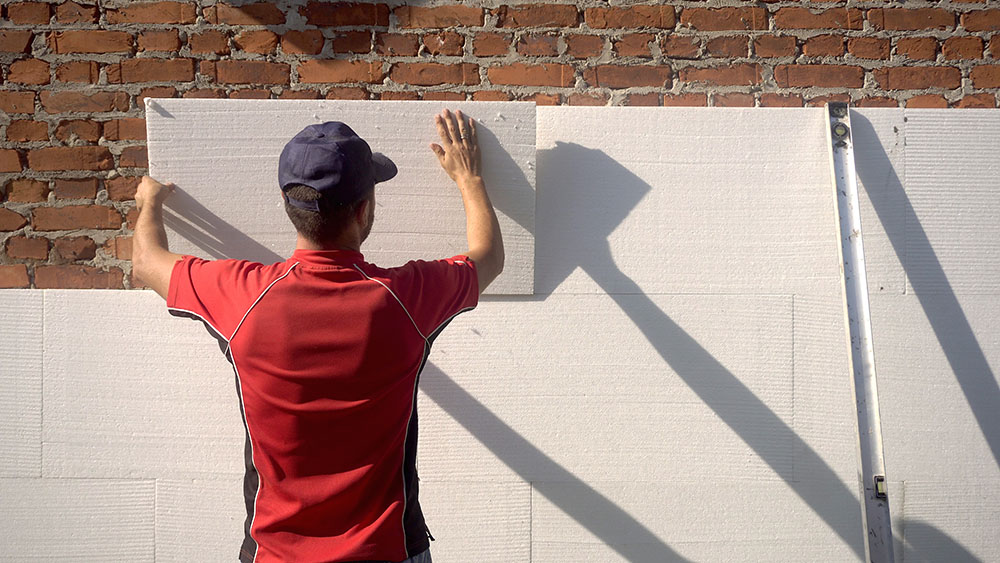 A person setting up drywall outside