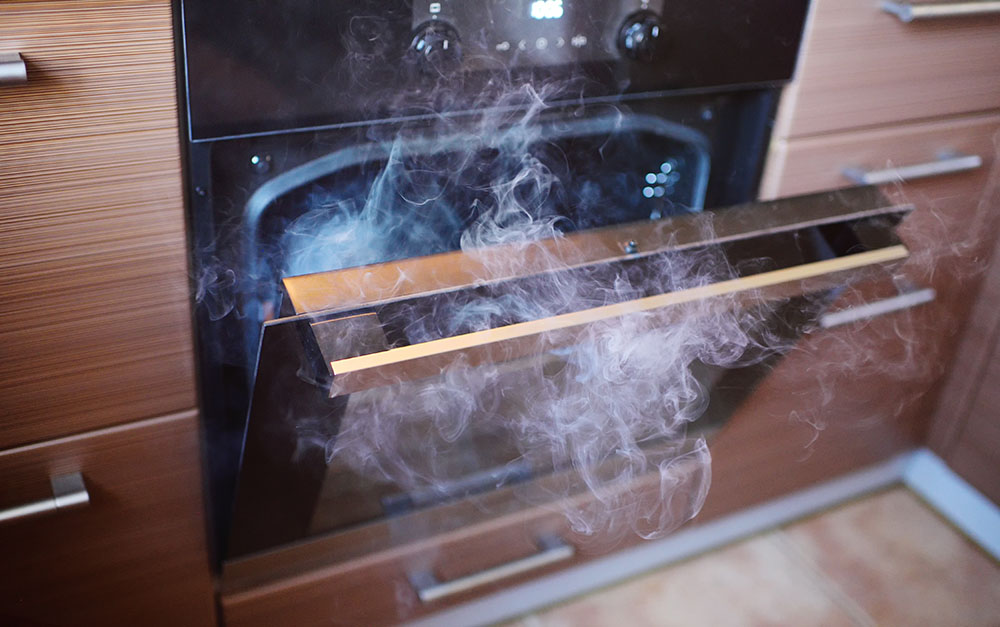An oven door open with smoke coming out