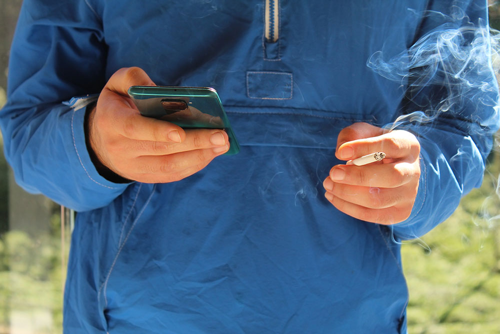 Man holding a phone while smoking a cigarette