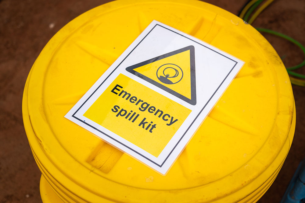 A yellow bucket marked with an 'emergency spill kit' sign