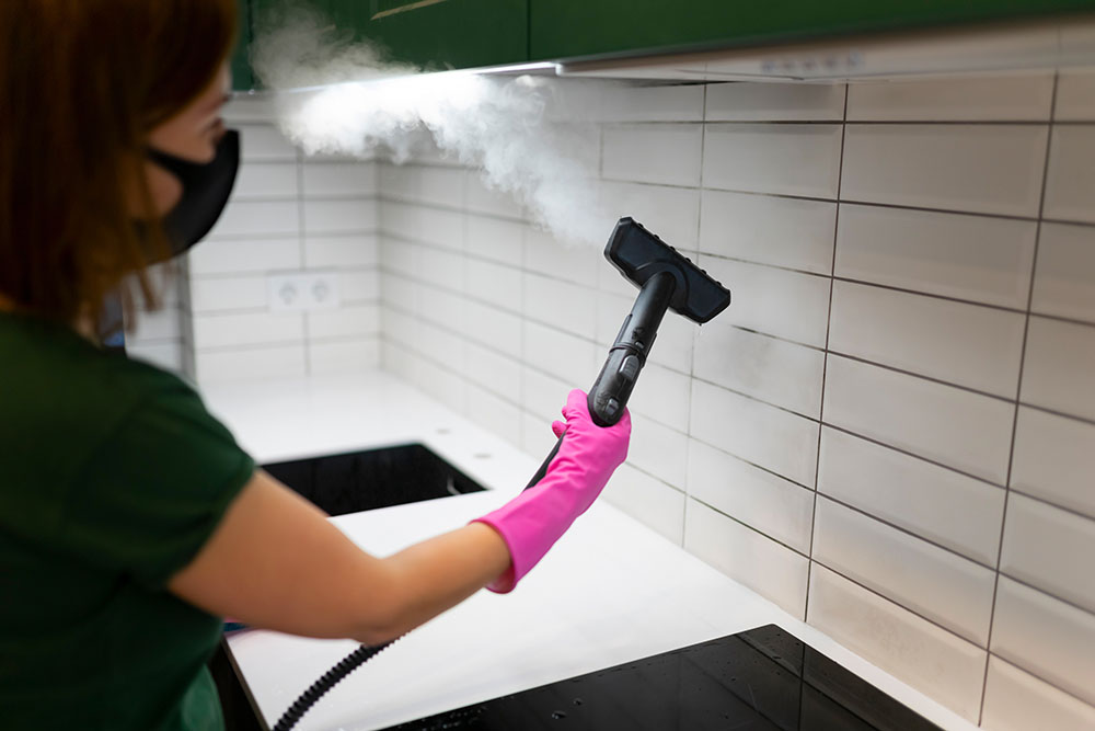 Woman steam cleaning kitchen tiles