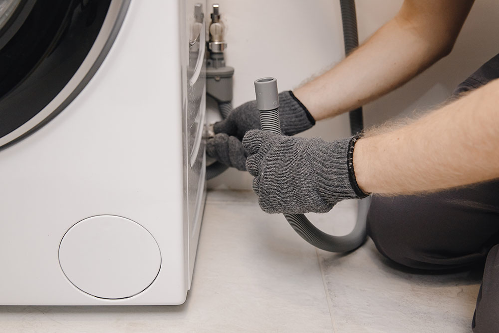 Plumber draining a washing machine drain pipe