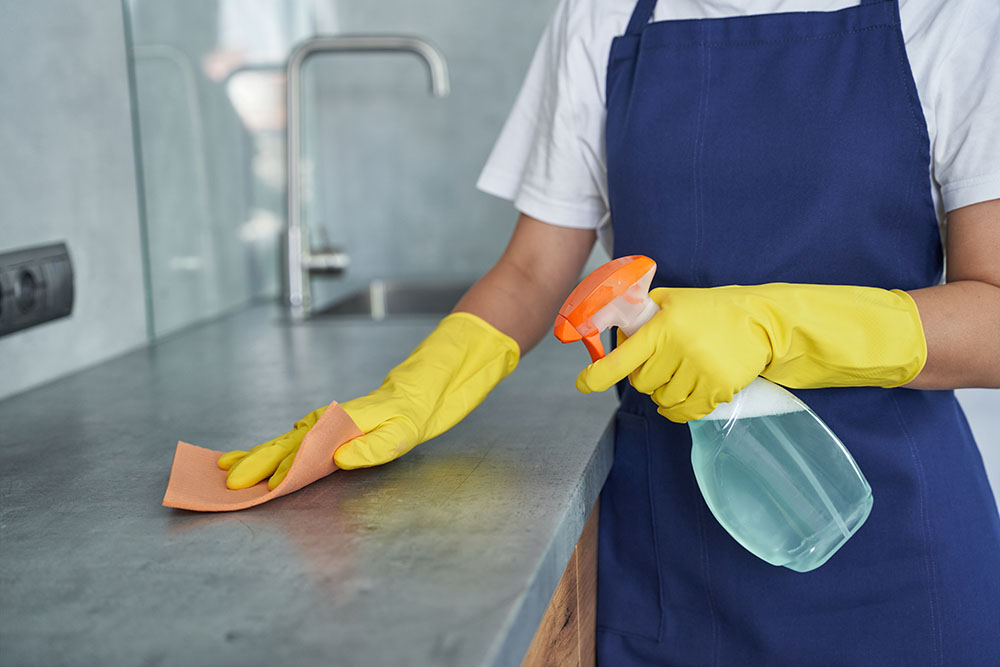 Woman cleaning commercial kitchen countertop