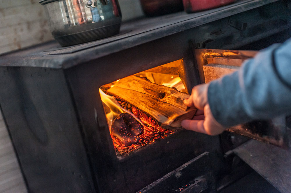 Man putting wood into wood burner