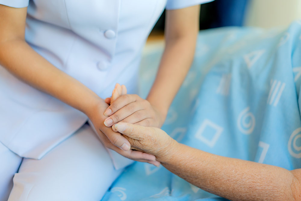 Nurse holding an older patients hand