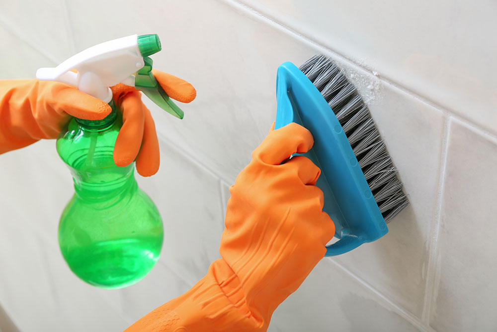 Someone cleaning bathroom tile with eco-friendly solutions