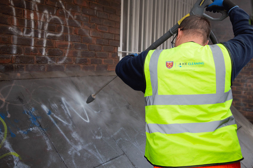 Cleaner removing graffiti with specialist equipment