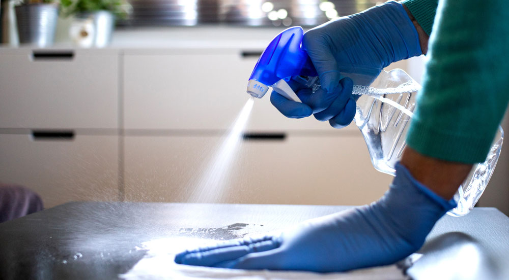 A cleaner spraying a surface with a cleaning product