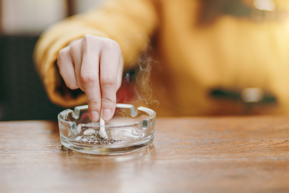 Someone putting out their cigarette in an ashtray