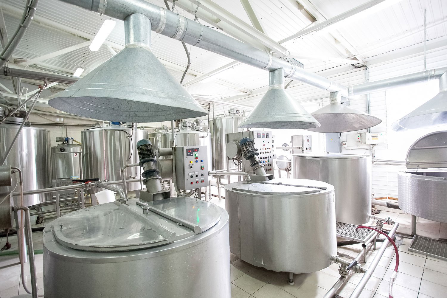 Food production facility with large metal vats and overhead ventilation