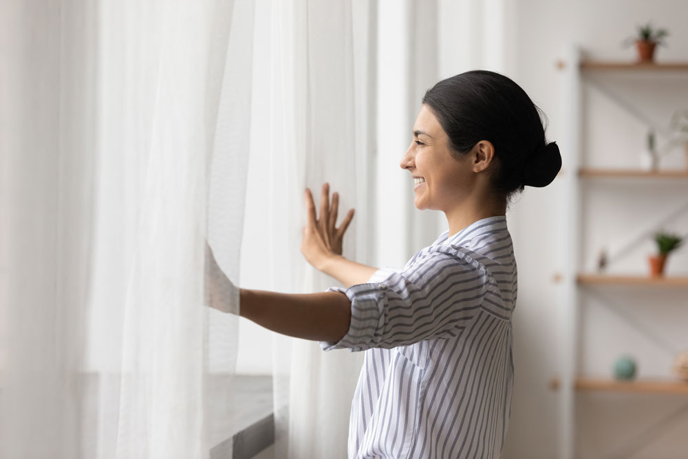 Woman opening curtains