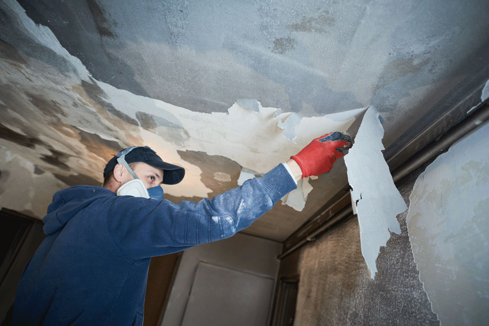 Someone removing soot from a ceiling