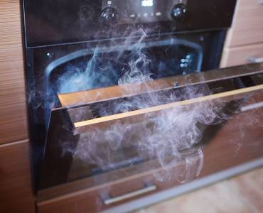 An oven door open with smoke coming out
