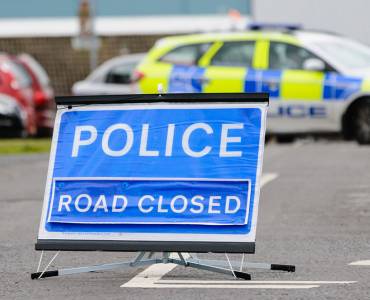 Cordoned off area with police sign and car