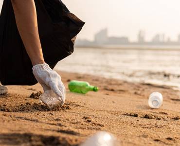 Person cleaning plastic bottles off the beach